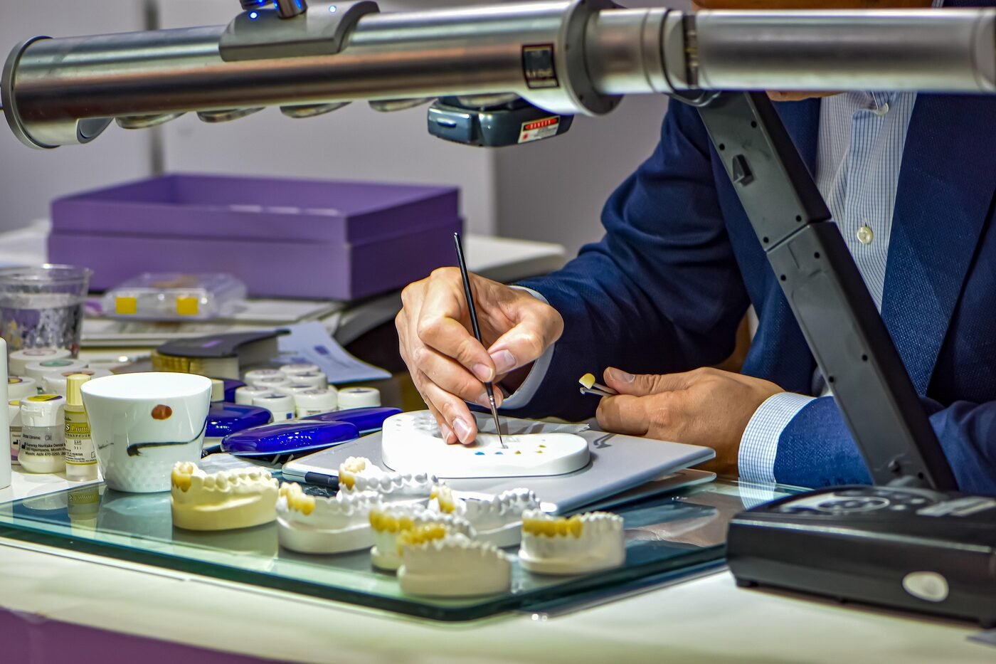 Zahntechniker schichtet Keramik mit dem Pinsel am Laborarbeitsplatz