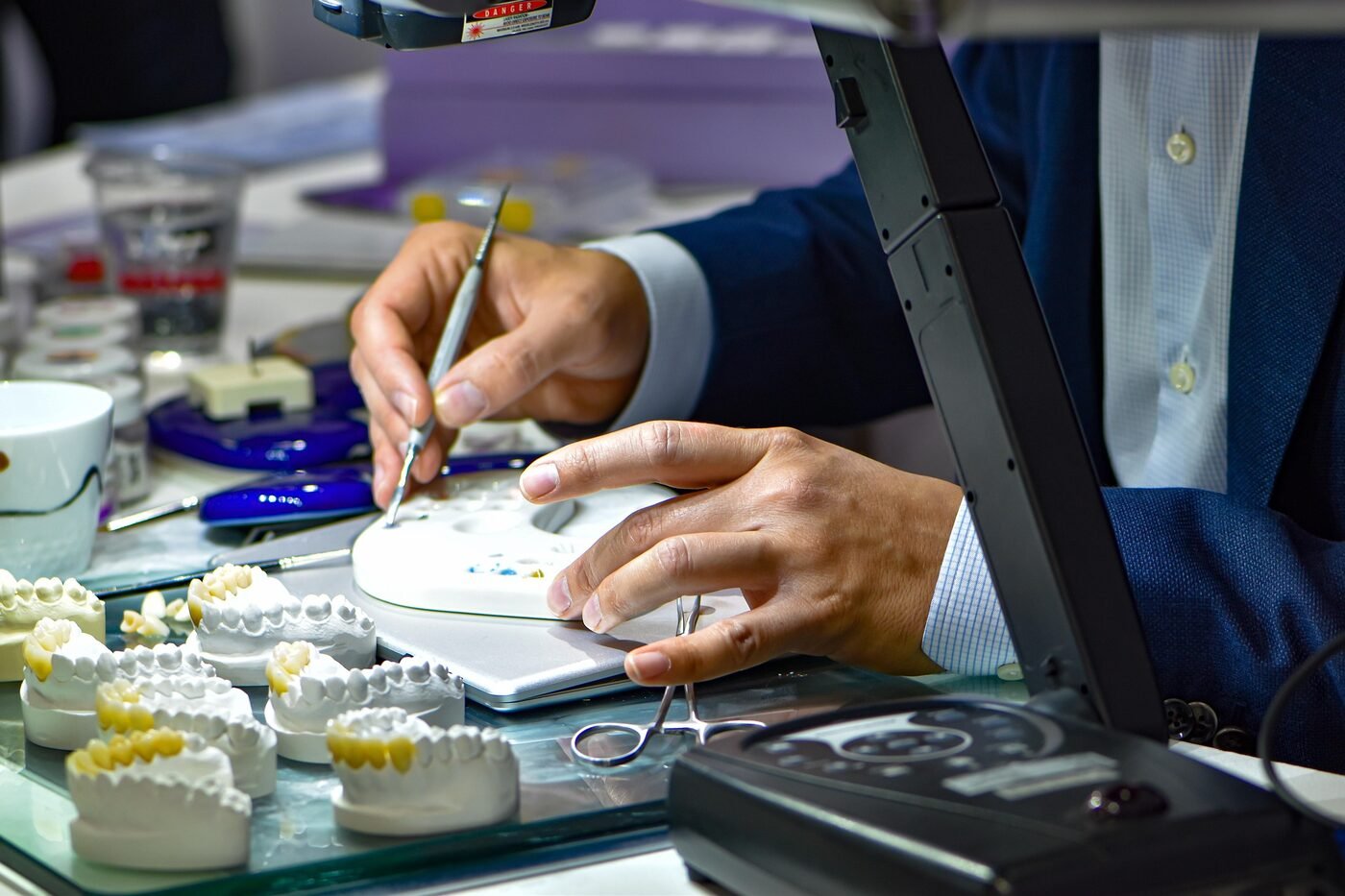 Zahntechniker arbeitet mit feinem Instrument an einer Keramikarbeit