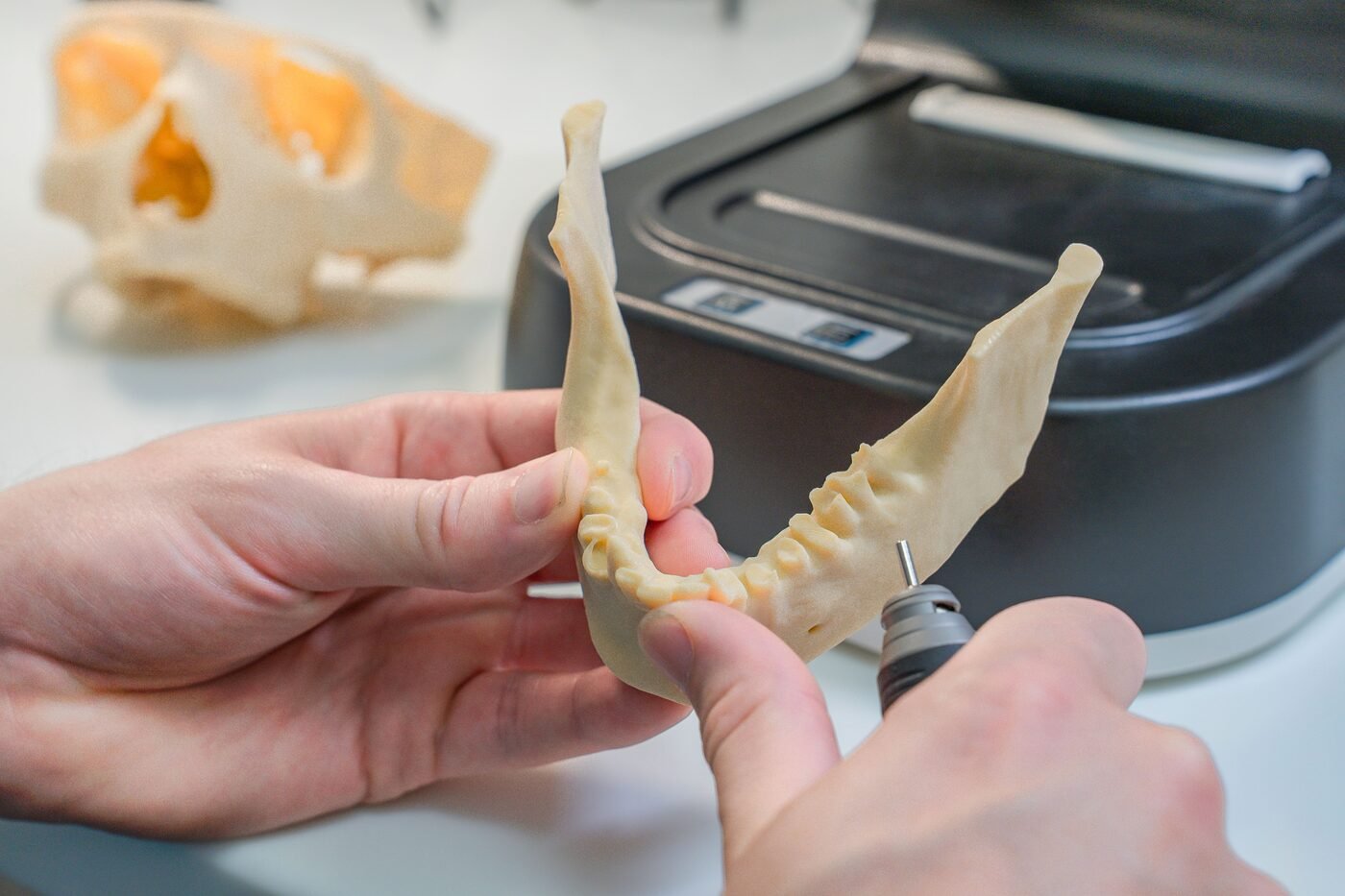 Zahntechniker bearbeitet ein Kiefermodell von Hand im Labor